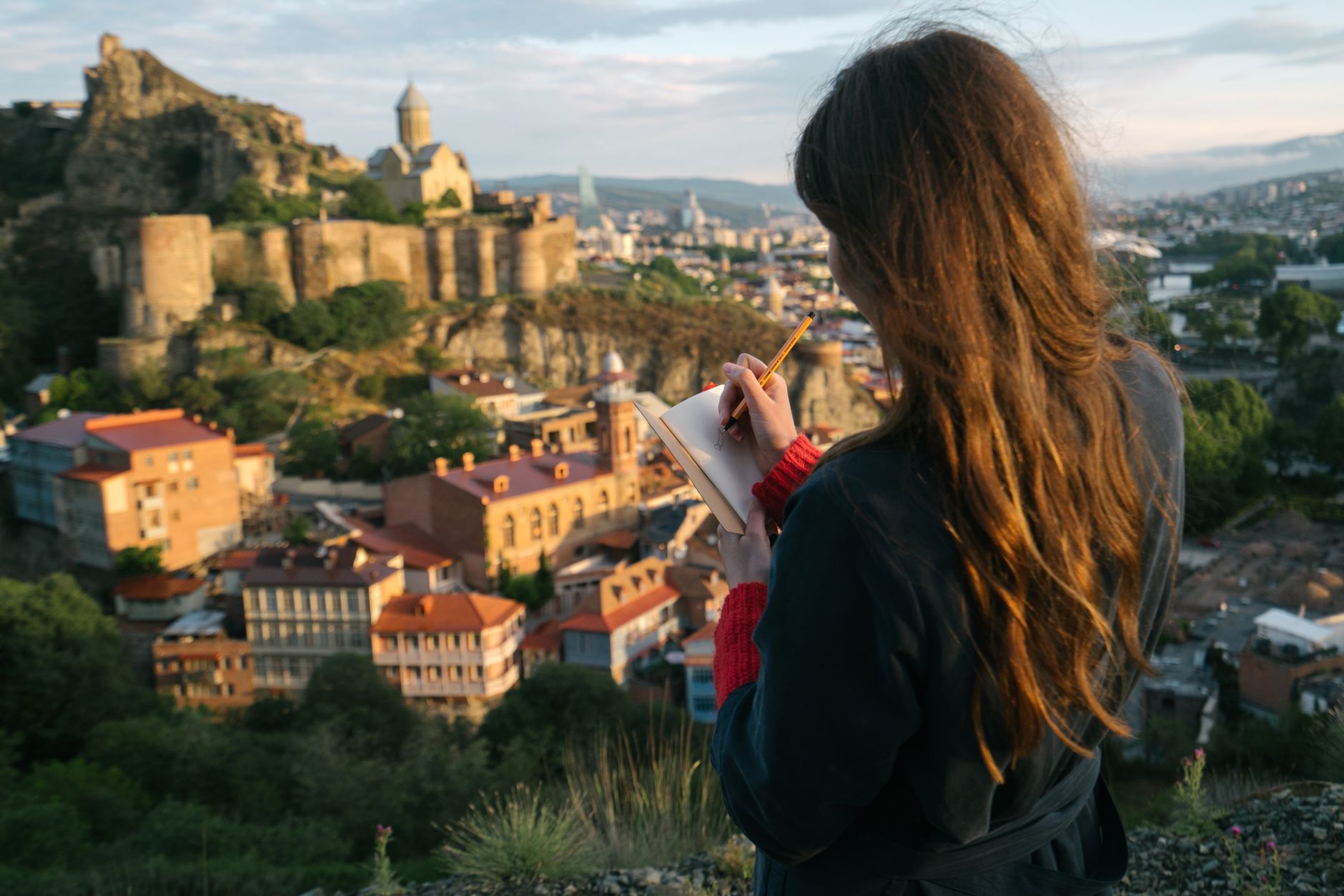 Travel author reviewing manuscripts overlooking an ancient mountain valley